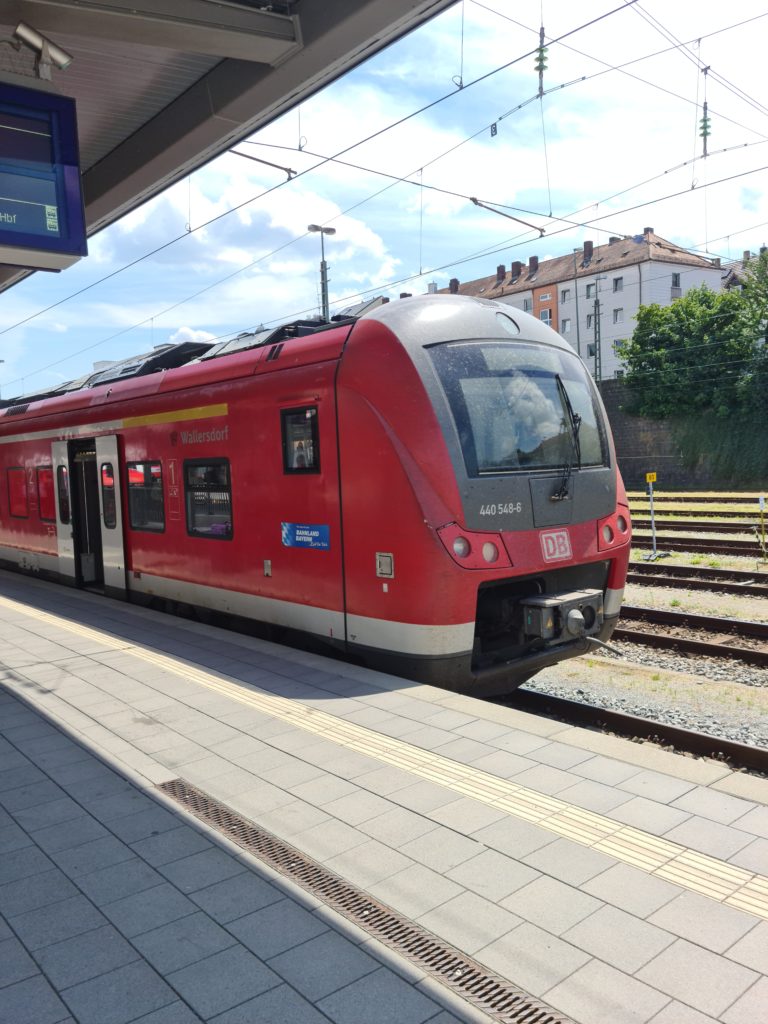 Bilde av et rødt tog ved rn perrong med dørene åpne.
